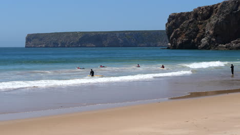 Unrecognizable-surfers-with-surfboard-on-beach-on-sunny-day