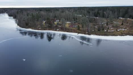 aerial view of a few vacation homes at the edge of a frozen lake in rural sweden