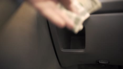 pov perspective of quickly grabbing cash from a compartment in a generic grey car