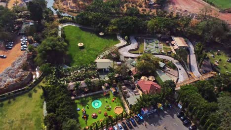 drone flying backwards over a large green playground in the central park of abuja, nigeria