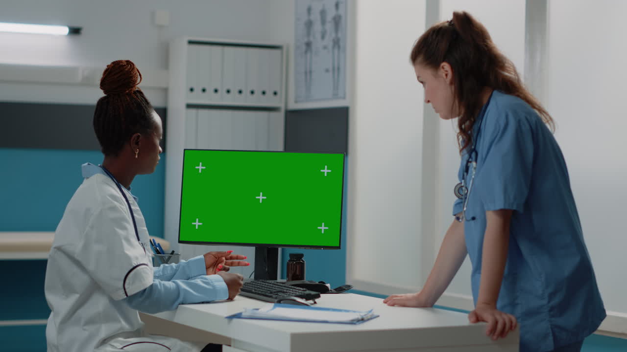 Doctors collaborating on a computer with a green screen