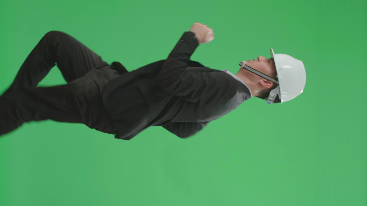 hombre de negocios en un traje y sombrero duro bailando en una pantalla verde