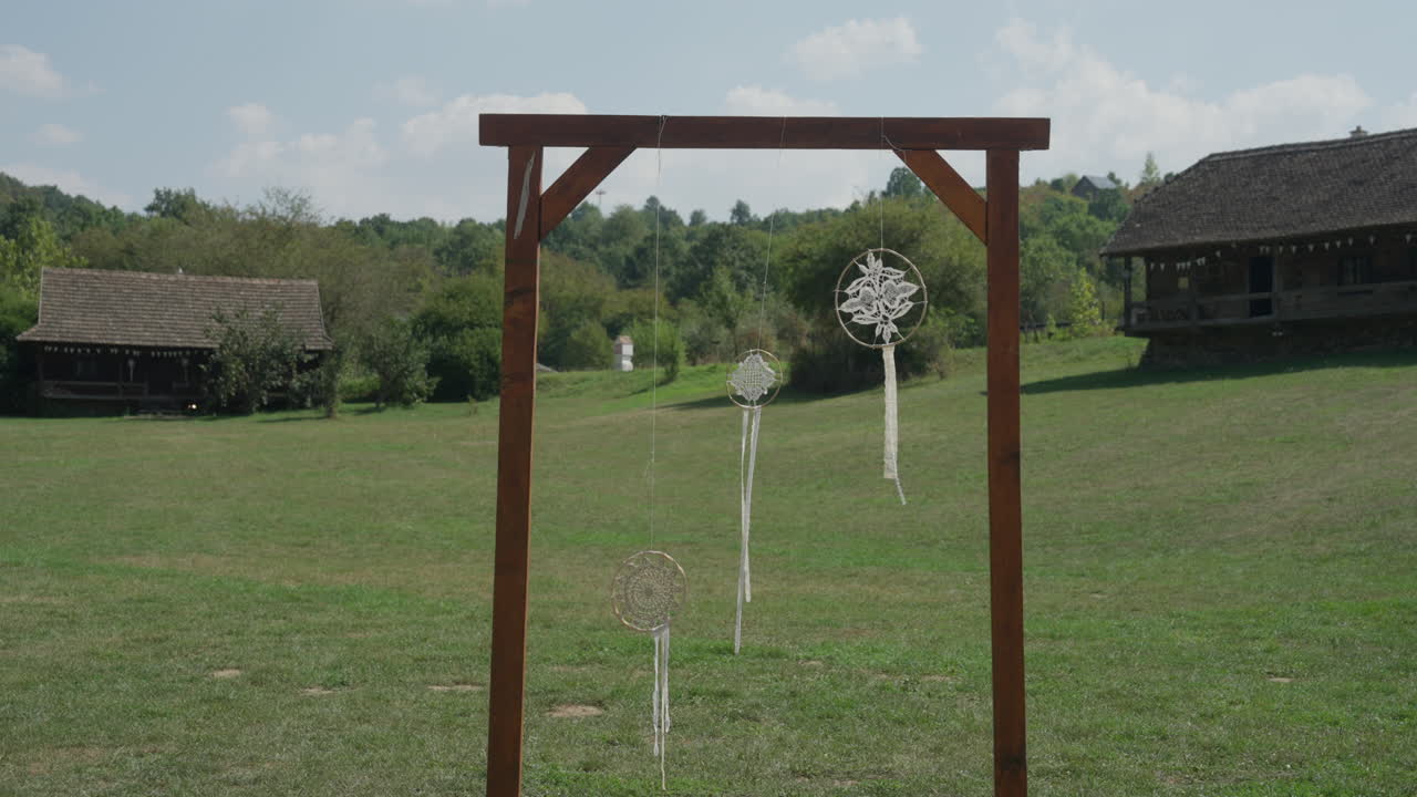 A beautiful white dream catcher swaying gently in the wind on a farm, adding a touch of serenity and boho charm to the rustic countryside setting.