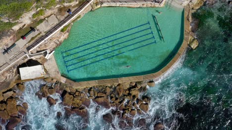 people swim at bronte baths with crashing ocean waves in summer