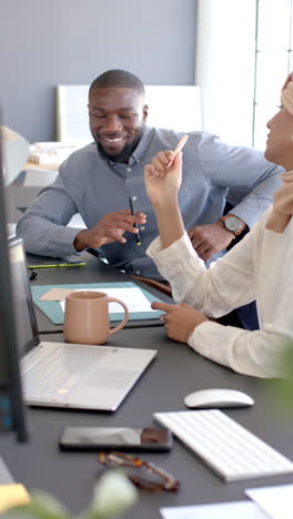 vertical video: collaborating in office, colleagues discussing project with laptop and tablet