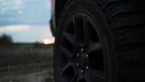 offroad stopped van car wheel close-up against sunset - revealing shot