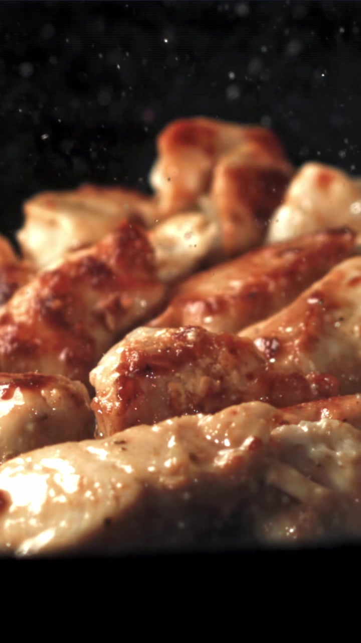 Primo piano di pezzi di pollo dorati che friggono in una padella