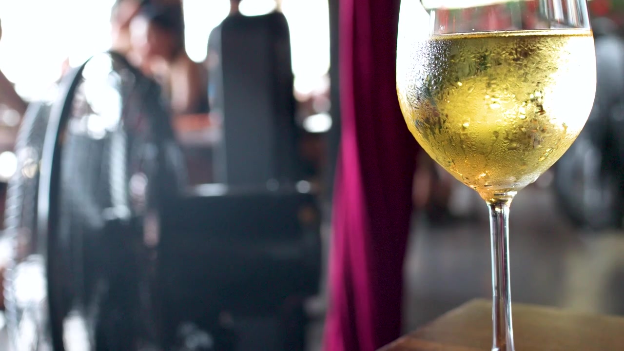 Vino bianco rinfrescante in un bicchiere su un tavolo con sfondo sfocato