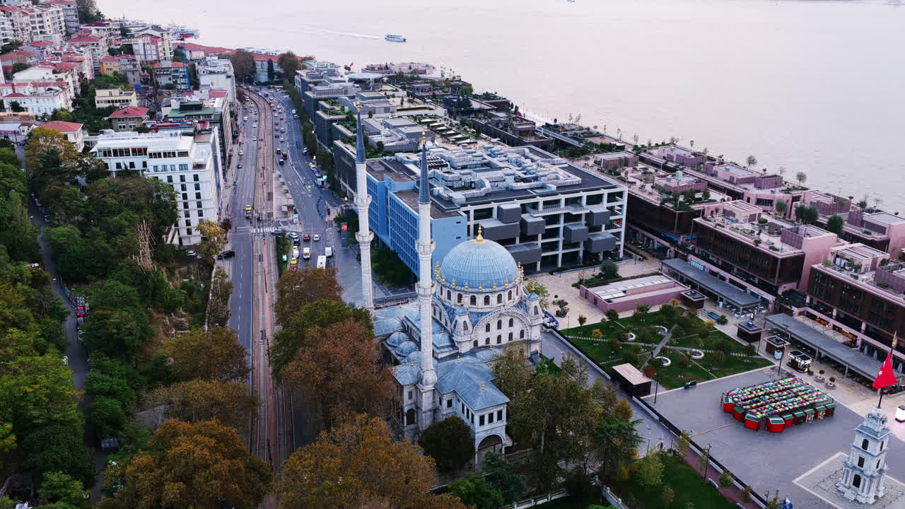 Aerial view of Dolmabahçe Mosque with its elegant domes and minarets beside modern buildings near the Bosphorus shoreline