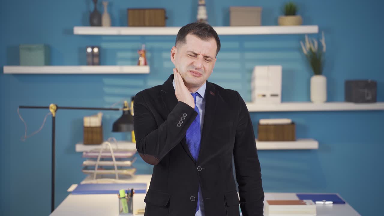 사업가는 그의 목을 잡고 그의 목을 고통스럽게 문지르고 있습니다.