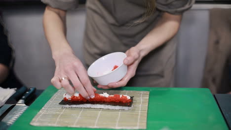 woman chef filling japanese sushi rolls. hands of woman chef filling japanese sushi rolls with rice on a nori seaweed sheet