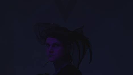 gothic man in veil with feathers posing in dark studio