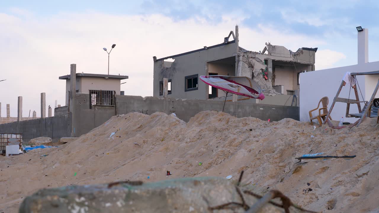 해변 우산 의 잔해 가 폭격 된 집 의  ⁇ 데기 밖 에서 바람 에 날아간다