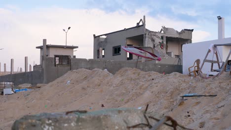 Remnants-of-a-beach-umbrella-blow-in-the-wind-outside-the-shell-of-a-bombed-house