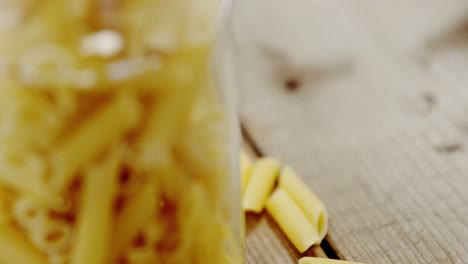 penne pasta overflow of the jar on wooden table