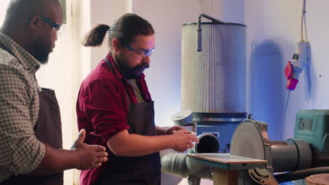 trabajador aprendiendo de un profesional de carpintería cómo usar la máquina de molienda