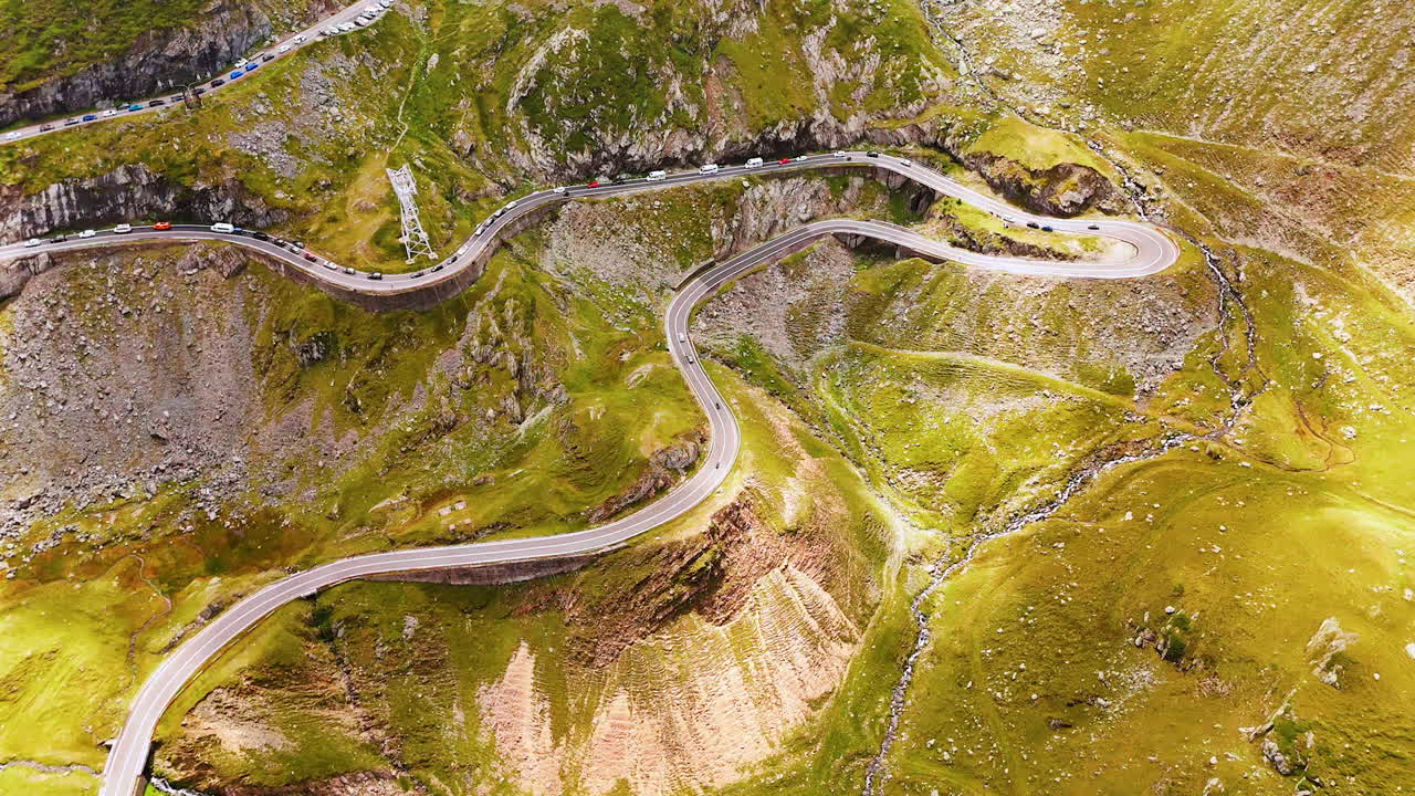 Multiple cars move and stand on the famous Transfagarash highway. Drone flight over the rocky landscape of Romania