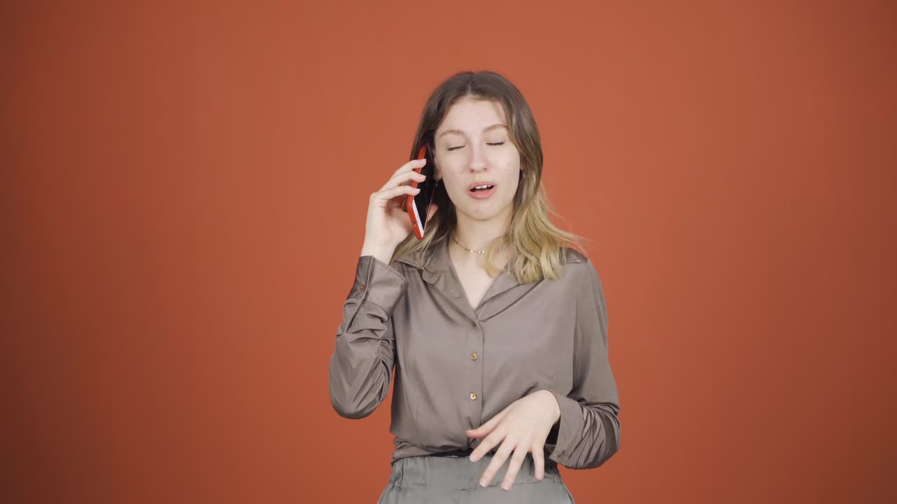 행복한 젊은 여자가 전화로 얘기하고 있습니다.