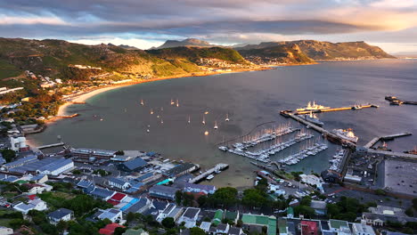 aerial cinematic drone sunrise simon's town naval boat marina fishing small quite city cape town south africa early sunlight clouds table mountain fish hook muizenberg penguins upward movement