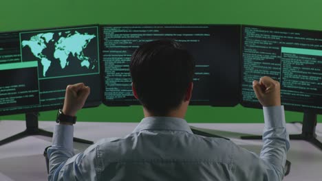 행복한 아시아 남성 개발자가 그린 스크린 스튜디오에서 여러 컴퓨터 화면으로 코드를 작성하는 동안 축하하는 뒷면