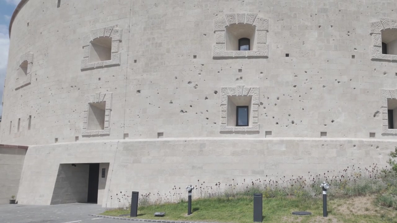 Video 4K di una spessa muraglia di fortezza con piccole finestre e fori di proiettile su tutta la parete a Budapest, Ungheria