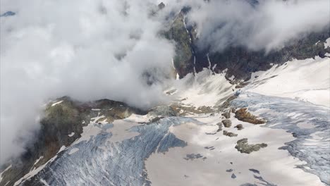 low clouds over susten pass - snowy mountain pass in swiss alps in switzerland