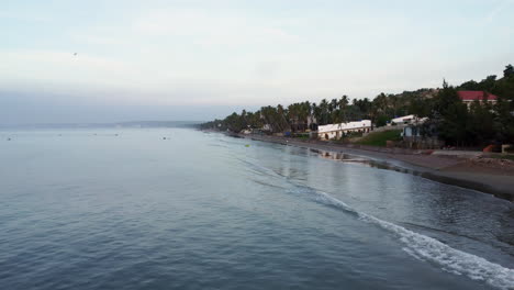 Aerial,-calm-ocean-waves-rolling-into-tropical-beach-shore,-early-morning-in-Vietnan