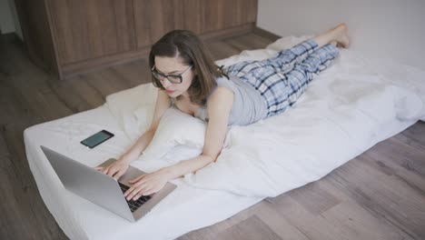 Barefoot-woman-using-laptop-on-mattress