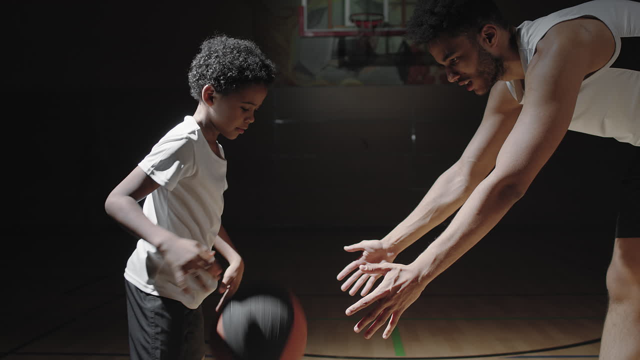 Male Basketball Player Teaching Boy to Dribble Ball