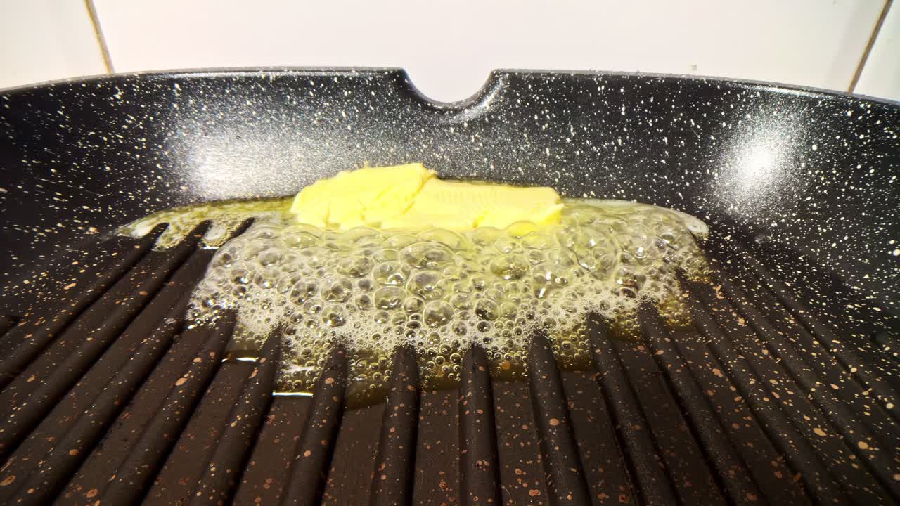 Melting butter on a grill pan, sizzling and bubbling, shot indoors