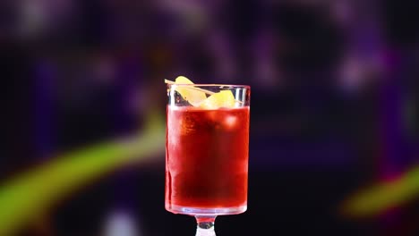 a vibrant negroni cocktail is prepared in a dimly lit setting with a colorful, blurred background
