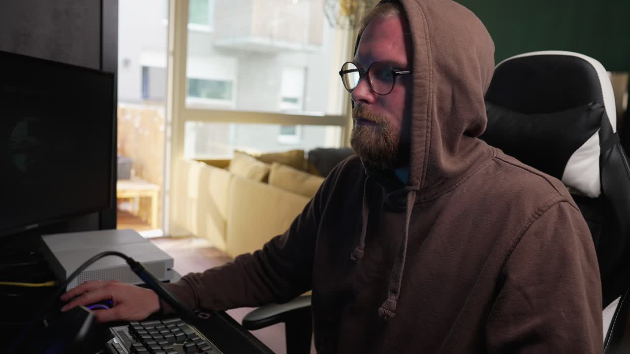 COMPUTERS - Man in a hoodie uses mouse while surfing the internet, medium shot