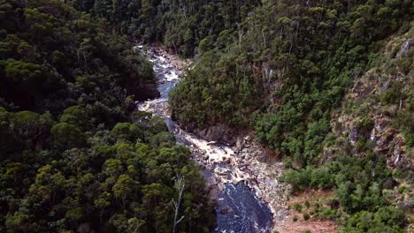 Aerial-drone-bird's-eye-view-over-river-passing-through-Leven-Canyon-in-Tasmania,-Australia-on-a-sunny-day