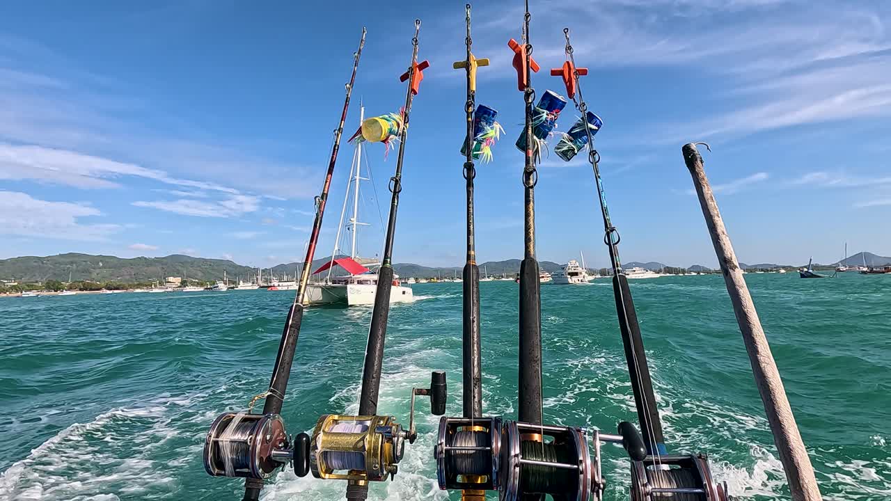 Fishing rods on a catamaran navigate vibrant Phuket waters under clear skies, capturing a serene and adventurous mood
