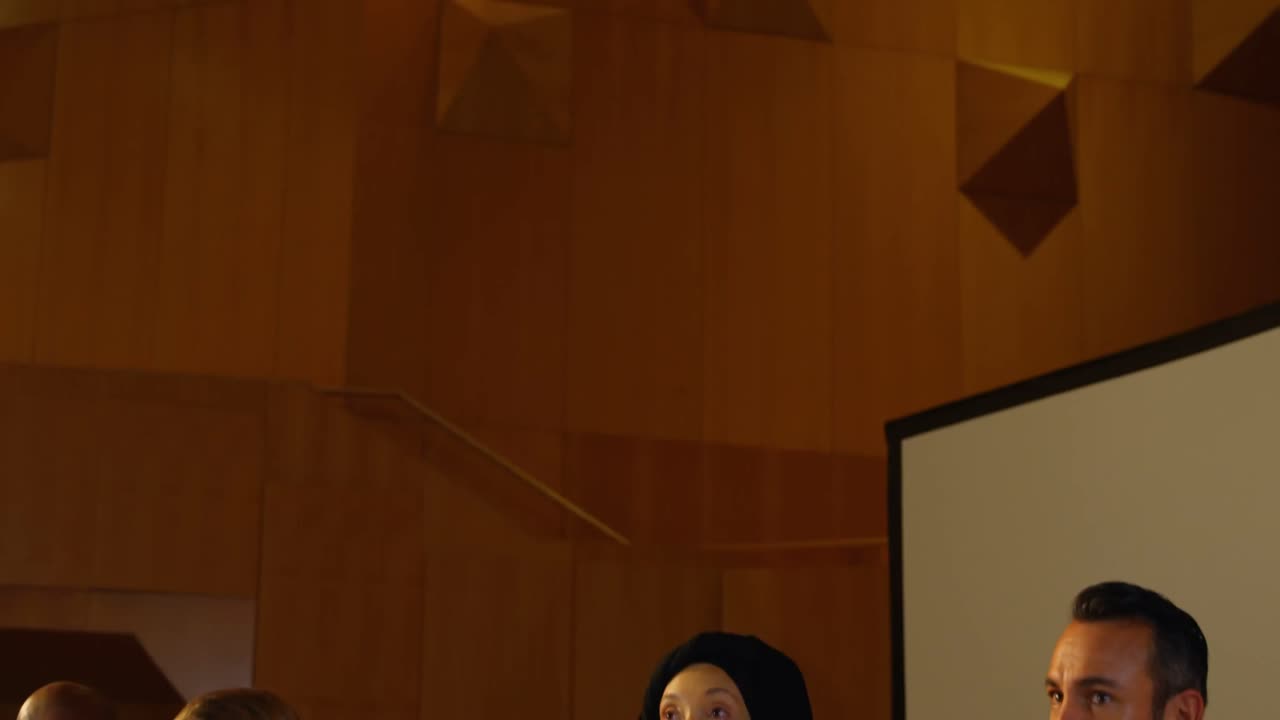 joven mujer caucásica hablando en altavoz en la mesa en el auditorio 4k