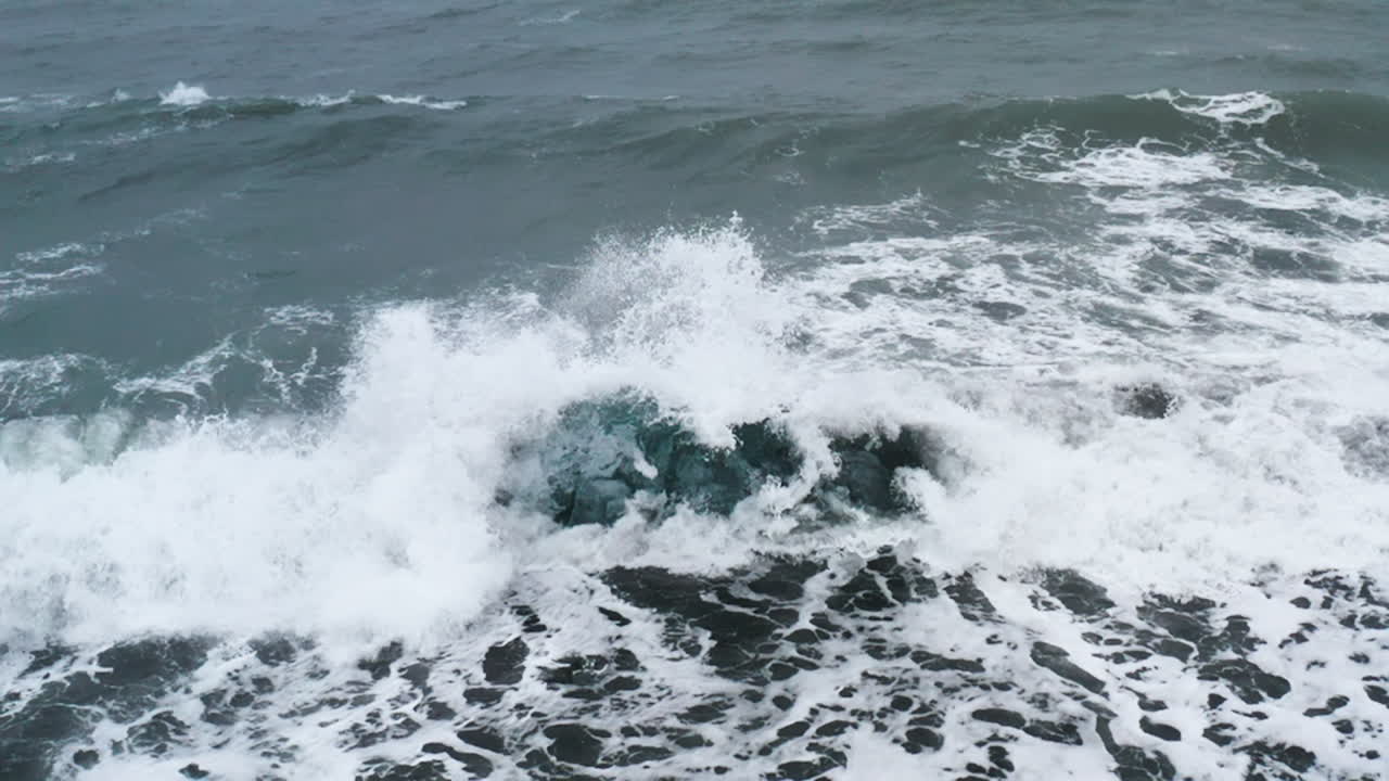 아이슬란드의 다이아몬드 비치에 있는 아름다운 얼음 바위 위에서 파열되는 파도의 놀라운 드론  ⁇