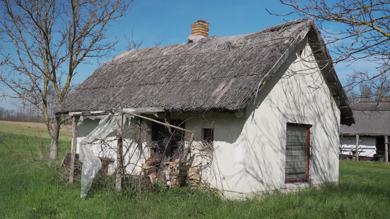 Small countryside house with thatched roof and overgrown yard