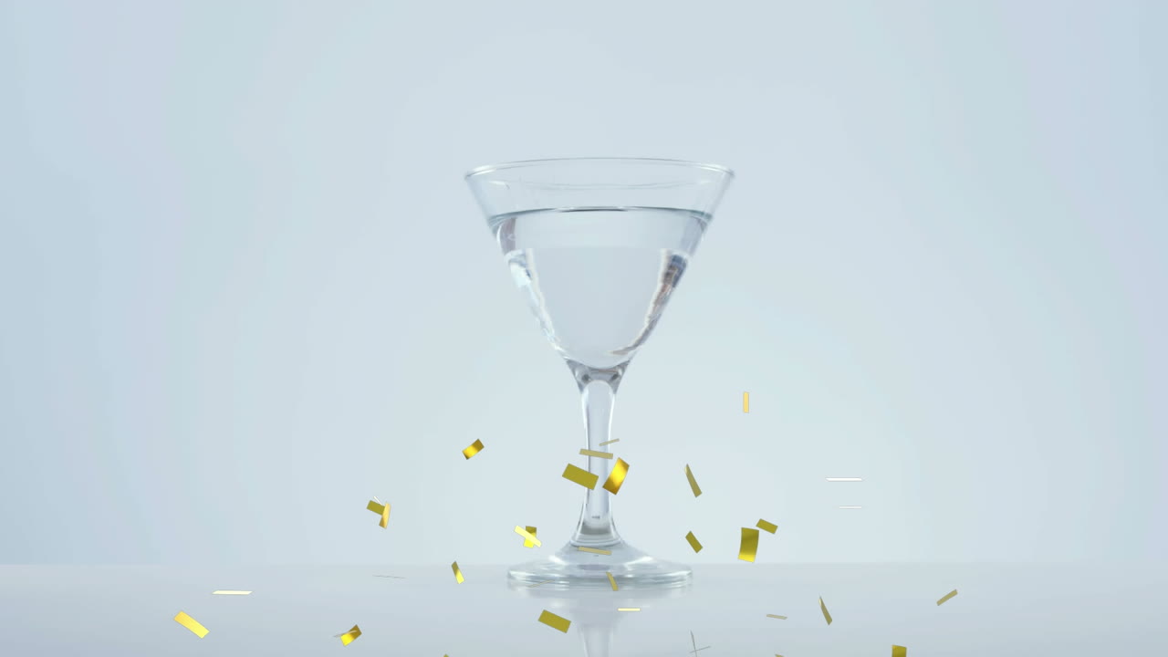 골든 콘페티가 올리브 위로 떨어지고 회색 배경에  ⁇ 테일 잔으로 떨어집니다.