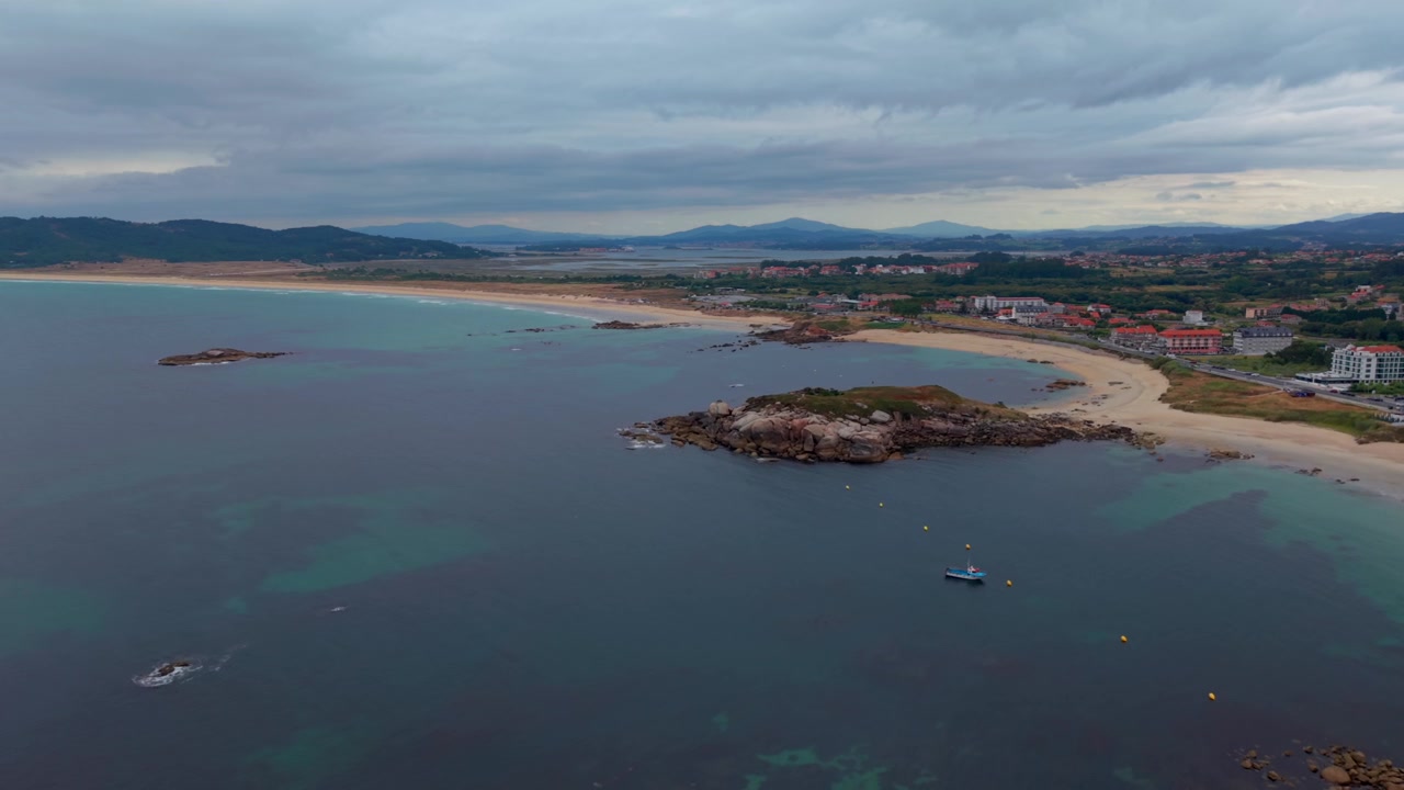 Luftfoto - Lange sandstrande ved A Lanzada med en klippeø og et kapel på en odde nær Sanxenxo, Spanien