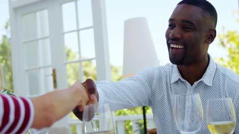 friends shaking hands while having meal