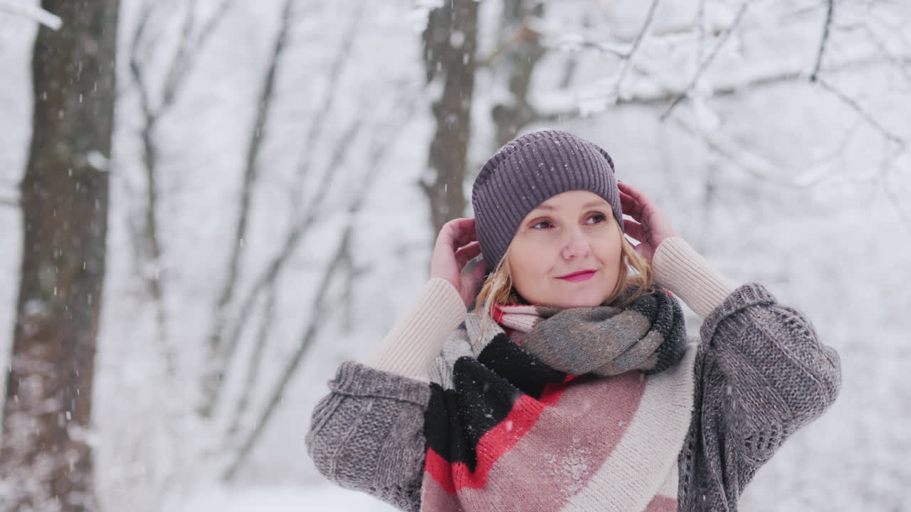 젊은 여자가 눈 덮인 숲에서 산책을 즐긴다
