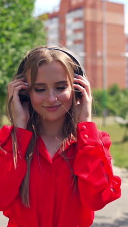 woman listening to music on headphones. young beautiful woman in the city with headphones listening to music. vertical video