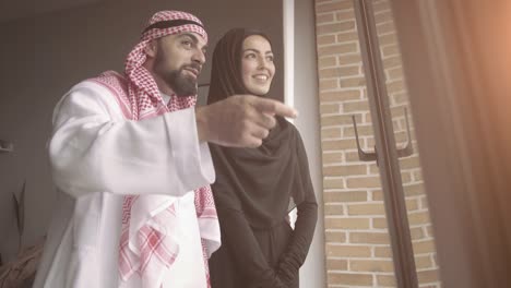 arab couple looking throught window at home.