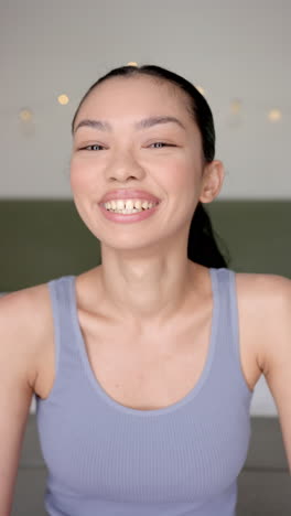 vertical video: smiling woman in casual tank top looking at camera, feeling happy and relaxed