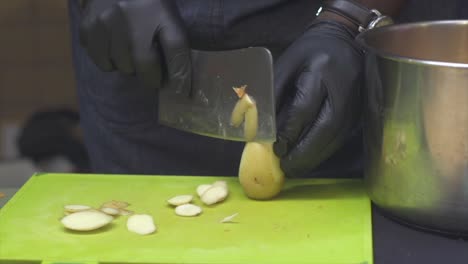 piel de patata pelada a mano con un cuchillo de carnicero en una tabla de cortar verde, filmada de cerca
