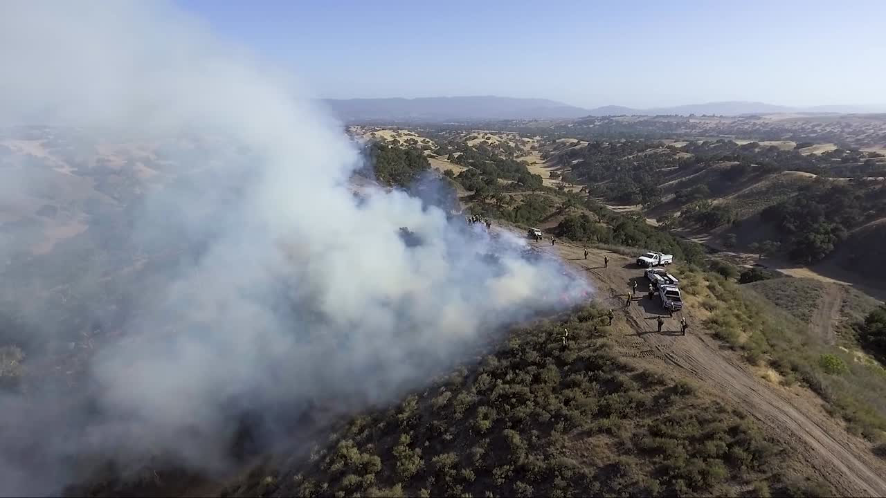 los camiones de bomberos se sientan encima de una cresta en llamas