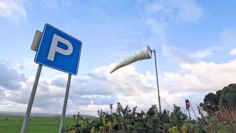 parking sign and wind sock in open field