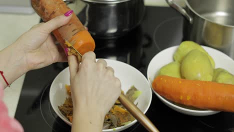 Female-housewife-hands-peeling-carrot-in-the-kitchen.