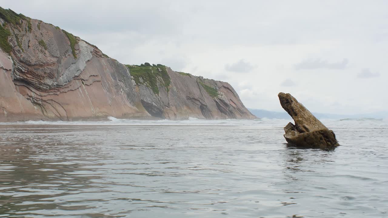 Shallow water with exposed rock strata at Itzurun Beach Spain, low angle