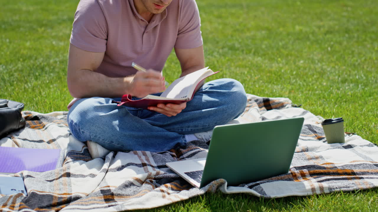 Online manager discussing project by video call sitting at green grass closeup